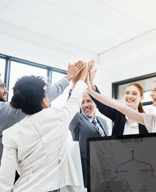 Shot of a group of businesspeople high-fiving in the office.